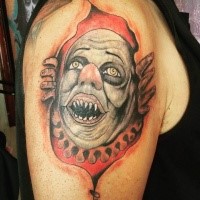 Old school illustrative style colored ripped skin tattoo on shoulder with demonic clown face