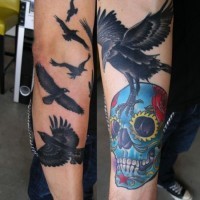 Tatuaje en el antebrazo,
bandada de cuervos con calavera de azúcar
