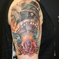 Old school nautical themed on shoulder tattoo of pirate ship with rose and lettering