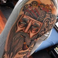 Oldschool bemalter und gefärbter rauchender Seemann mit Leuchtturm und Schiff Tattoo am Arm