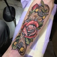 Old school style broken skateboard and red roses forearm tattoo with pale violet haze