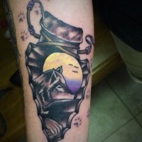 Old school style colored antic arrow head tattoo on forearm stylized with moon and wolf