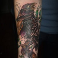 Tatuaje en el antebrazo, cuervo oscuro siniestro con cráneo pequeño