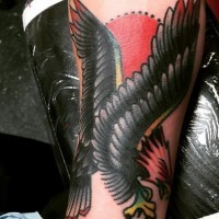 Tatuaje en el antebrazo,
águila negra extraordinaria con sol rojo, old school
