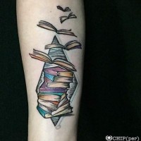 Tatuaje en el antebrazo, pila de libros que vuelan y figura geométrica