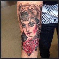 Old school style colored forearm tattoo of beautiful woman with rose and bear helmet
