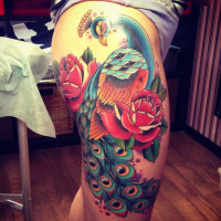 Old school style colored thigh tattoo of large peacock with flowers