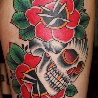 Old school style colored thigh tattoo of typical roses and human skull