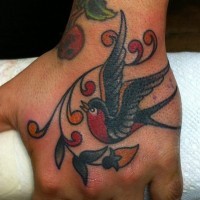 Old school tiny colored bird tattoo on hand with leaves