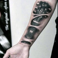 Tatuaje en el antebrazo, guitarra preciosa debajo de la piel