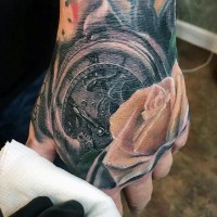 Tatuaje en la mano, reloj mecánico y rosa hermosa