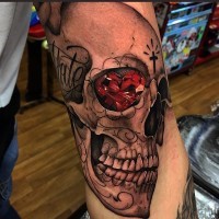 Tatuaje en el brazo,
cráneo con diamante rojo en el ojo