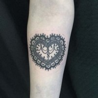 Ornamental style black and white heart shaped tattoo on forearm area