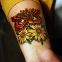 Tatuaje en la muñeca,
lechuza roja entre flores amarillas