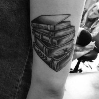 Tatuaje en el brazo, pila de libros gruesos negros blancos