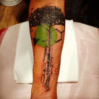 Photoshop style colored forearm tattoo of big tree with lettering and ornaments