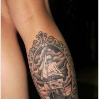 Pirate ship in frame with skull tattoo on leg