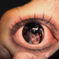 Portrait of a child in pupil of eyes tattoo on shoulder blade