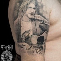 Portrait style black and white shoulder tattoo of Kurt Cobain with guitar