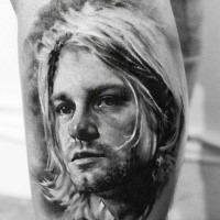 Portrait style black ink leg tattoo of Curt Cobain face