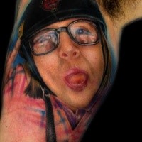 Portrait style colored biceps tattoo of funny woman face with helmet