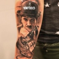 Portrait style colored forearm tattoo of Charlie Chaplin with old shoe