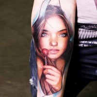 Portrait style colored forearm tattoo of girl with lollypop