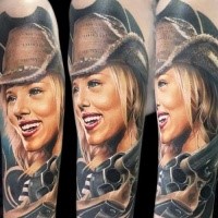 Portrait style colored shoulder tattoo of cowboy woman with revolver