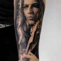 Portrait style detailed forearm tattoo of man with guitar