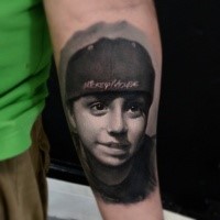 Portrait style very detailed arm tattoo of cute boy with lettering