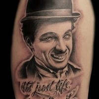 Portrait style very detailed shoulder tattoo of cool Charlie Chaplin with lettering