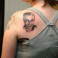 Kleines realistisches Tattoo-Porträt eines Mannes am oberen Rücken