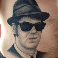 Reales Foto großer schwarzweißer mystischer Mann in Sonnenbrille Porträt Tattoo am Bauch