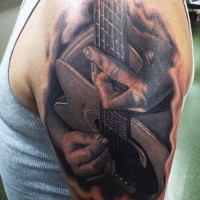 Tatuaje en el brazo, manos que tocan la guitarra acústica