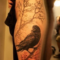 Real photo like colored very detailed crow tattoo on thigh stylized with lonely tree
