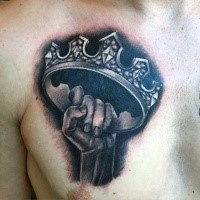Realism style black and white chest tattoo of hand holding crown
