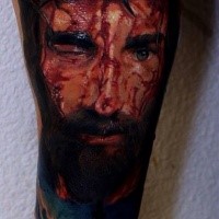 Realism style colored arm tattoo of bloody Jesus face with vine