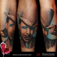 Realism style colored forearm tattoo of Merlin Manson in hat