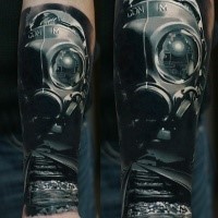 Realism style colored forearm tattoo of man with gas mask and lettering