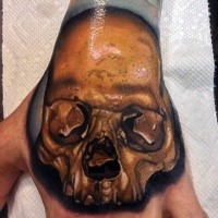 Realism style colored human skull tattoo on hand