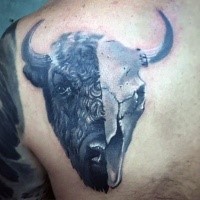Realism style very detailed scapular tattoo of half bull half skull