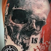 Realism style very detailed tattoo of large skull and lettering