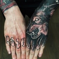Realistic furious dark colored wolf tattoo on hand with lettering on fingers