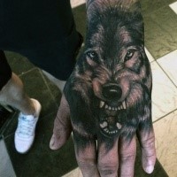 Realistic looking black and white hand tattoo fo roaring wolf head