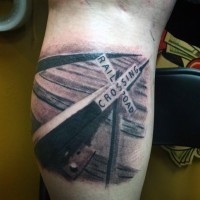 Realistic looking black and white rail road with sign tattoo on arm