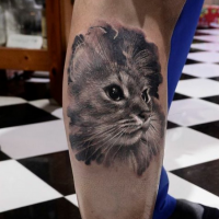 Realistic looking black ink leg tattoo of cute cat portrait