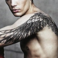 Realistic looking black ink wing tattoo on shoulder