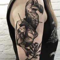 Tatuagem de braço superior estilo blackwork procurando realista de grande pássaro com folhas por Michele Zingales