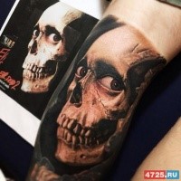 Realistic looking colored arm tattoo of creepy human skull with eyes