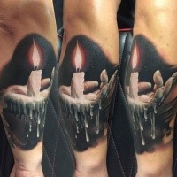 Realistic looking colored arm tattoo of hand holding candle